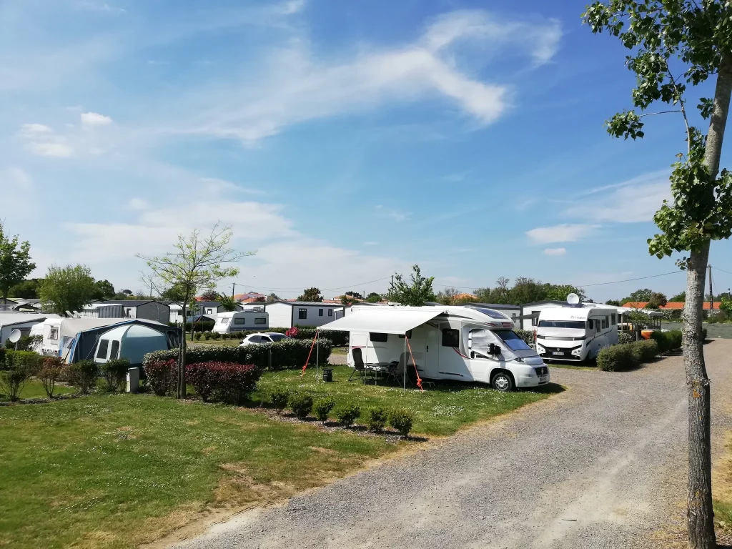 Camping avec caravanes et mobil-homes sous ciel bleu.