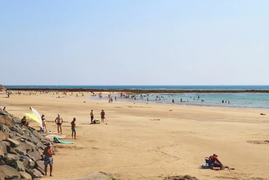 Plage avec baigneurs et parasols sous le soleil.
