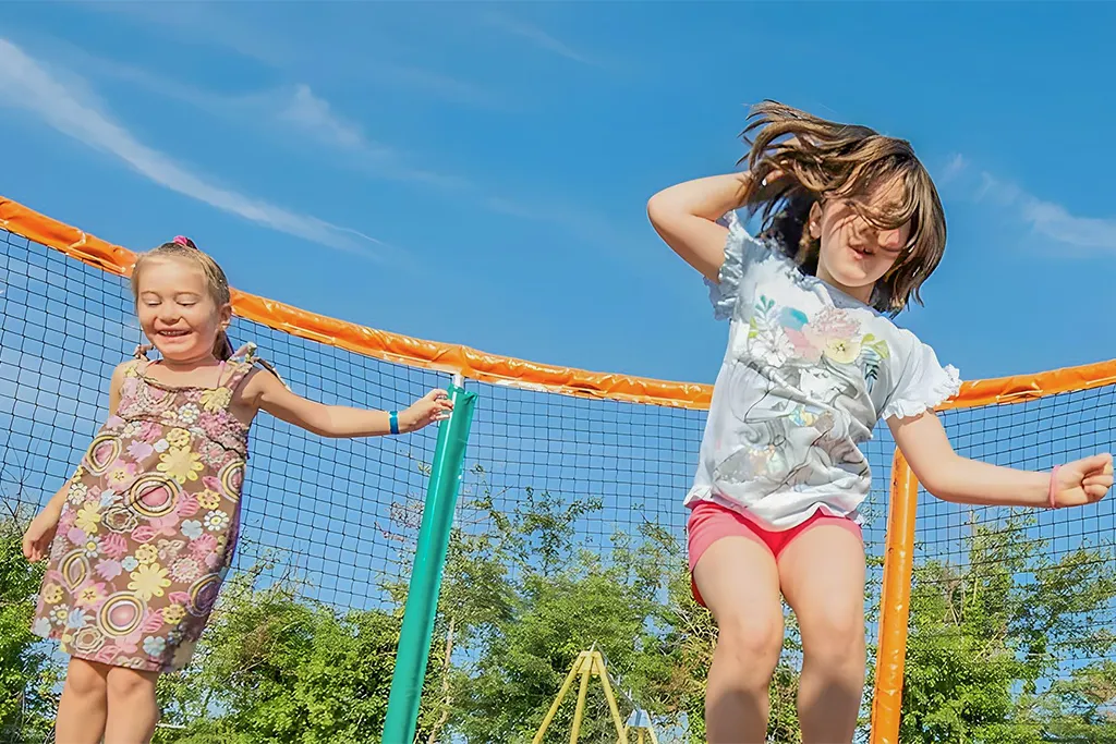 Enfants jouant sur un trampoline, ciel bleu.