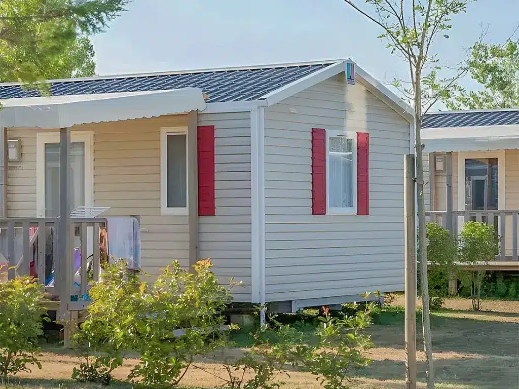 Mobil-home beige avec volets rouges.