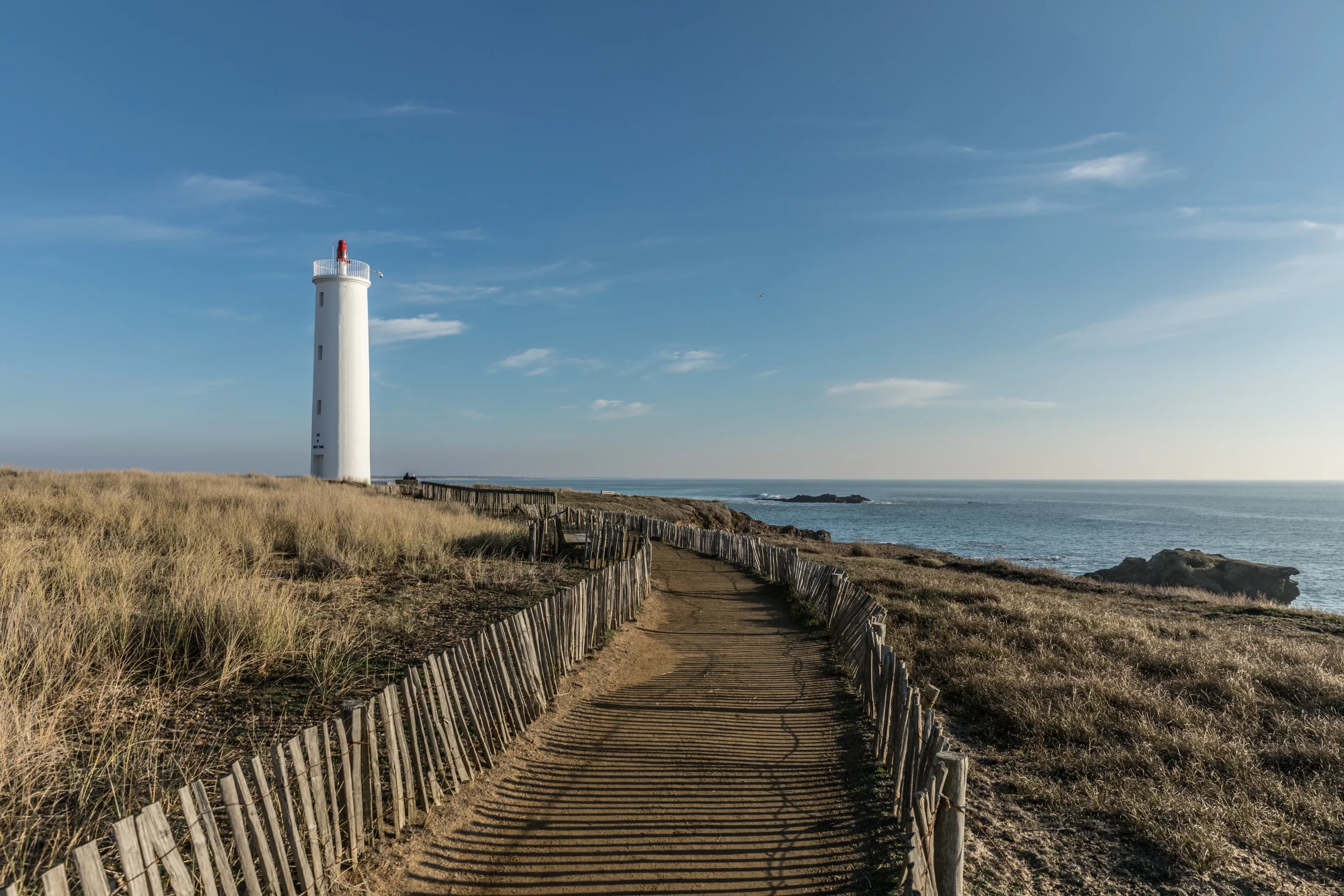 Phare blanc sur chemin côtier ensoleillé