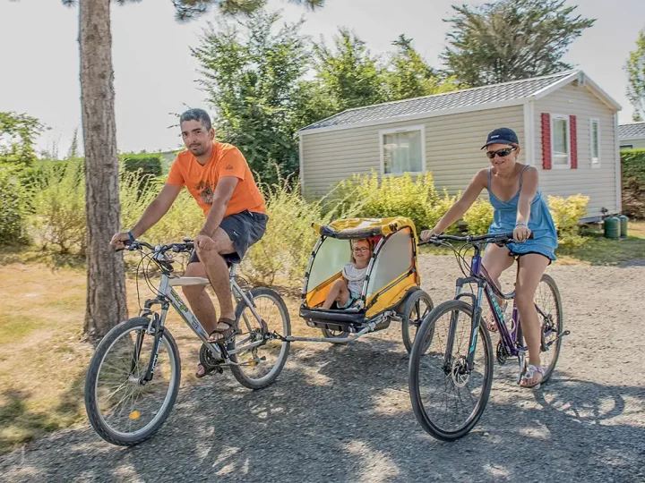 Famille à vélo avec remorque enfant.