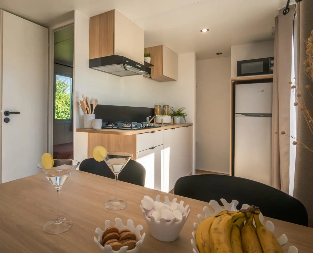 Cuisine moderne avec table, fruits et boissons.