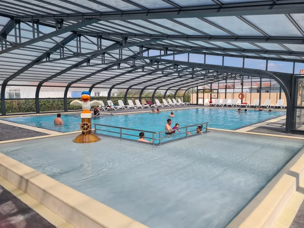 Piscine couverte avec baigneurs et jeux pour enfants.
