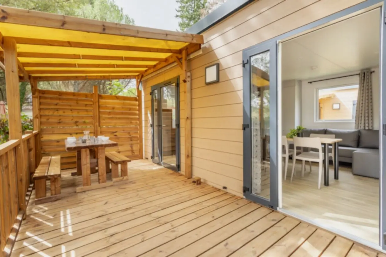 Terrasse en bois avec salon intérieur ouvert.
