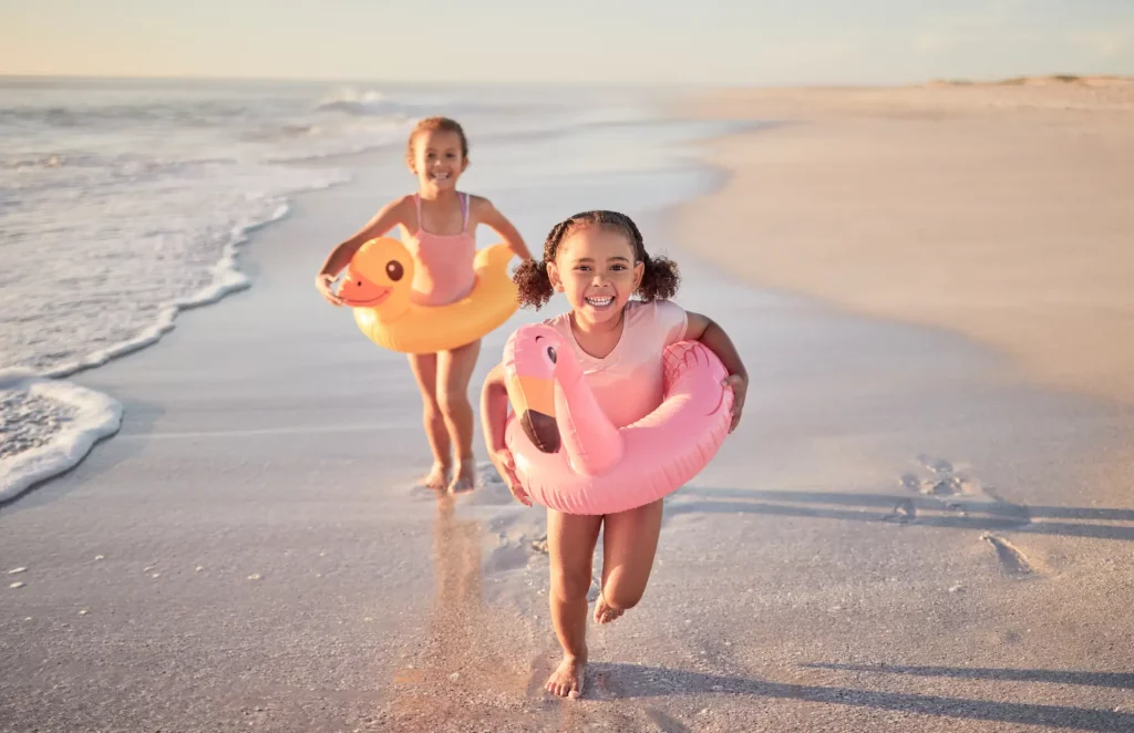 Enfants jouent sur la plage avec des bouées.
